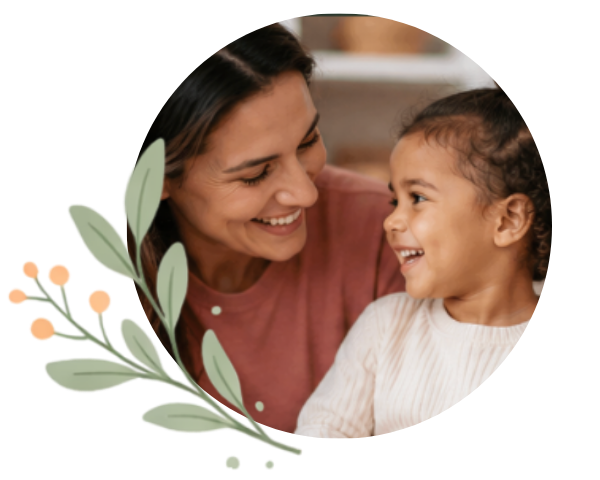 A smiling adult and young child share a joyful moment while making eye contact, framed within a circular photo. A soft green leafy illustration with peach-colored berries overlaps the lower-left edge of the circle, creating a warm, welcoming graphic that represents connection, support, and family.